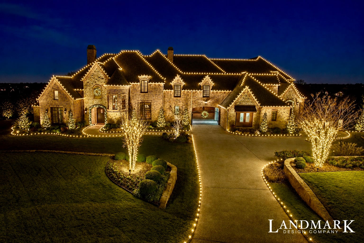 Large stone home with warm white lights tracing every roof gable.