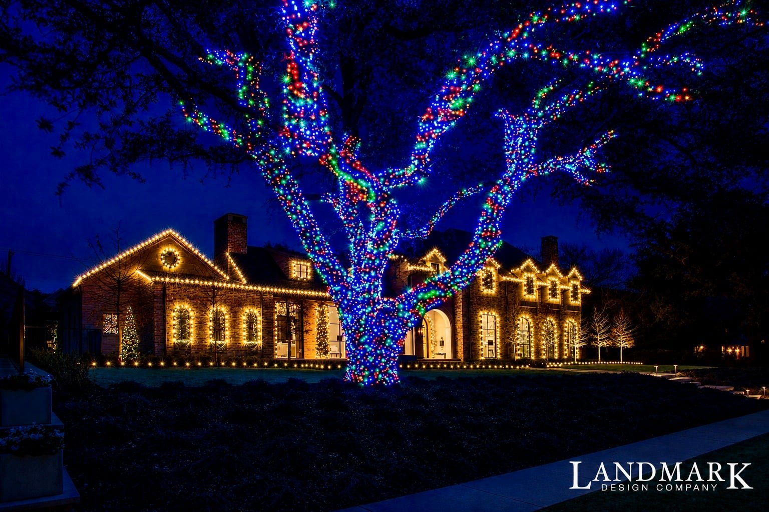 A beautifully decorated house with warm lights and colorful lights on a tree at night.